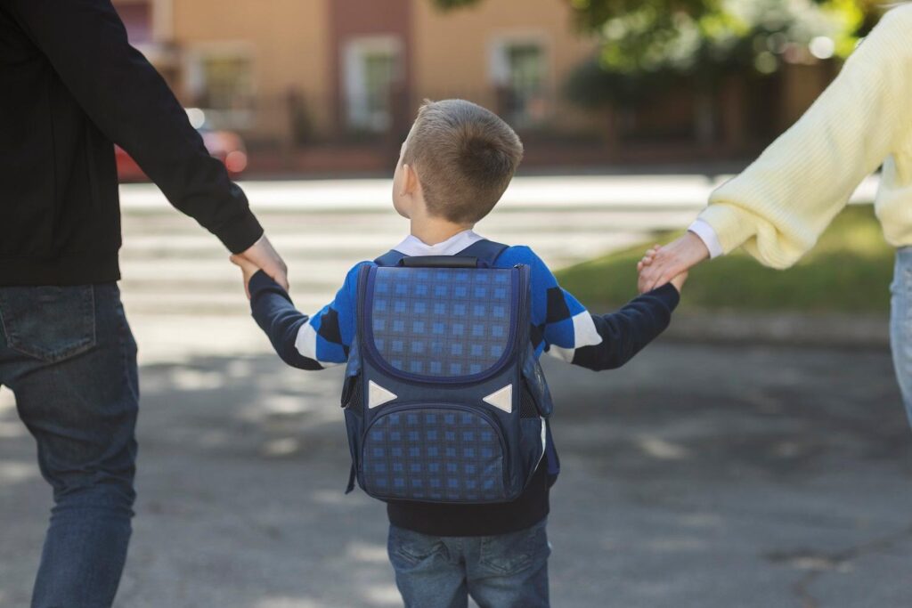 Pais levando criança para a escola tranquilamente após medidas para segurança nas escolas.