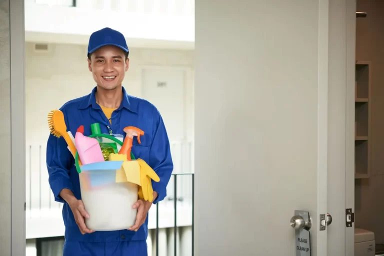 Imagem de homem de uniforme azul com produtos de limpeza na mão ilustrando a diferença entre limpeza e zeladoria.