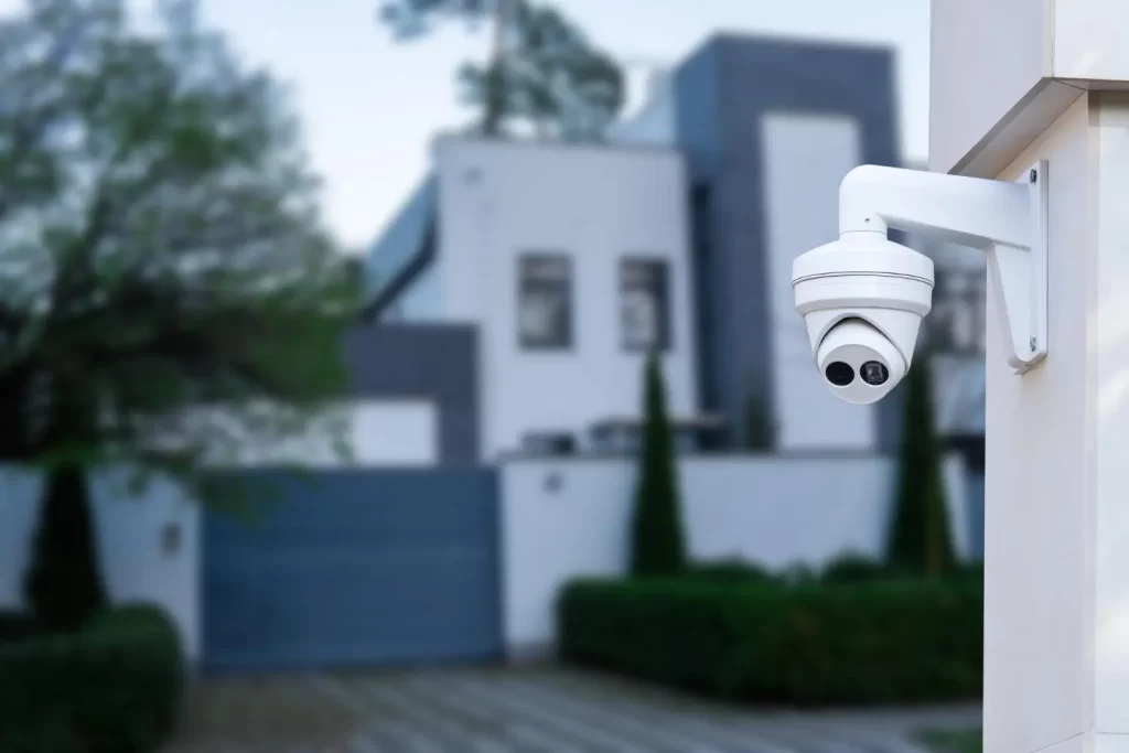 Uma câmera de segurança, com casa ao fundo, ilustrando como aumentar a segurança residencial