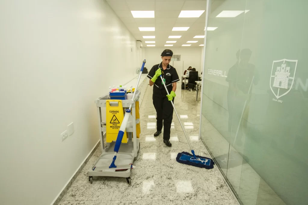 Auxiliar de limpeza fazendo a limpeza do chão e seguindo plano de higiene em escritório