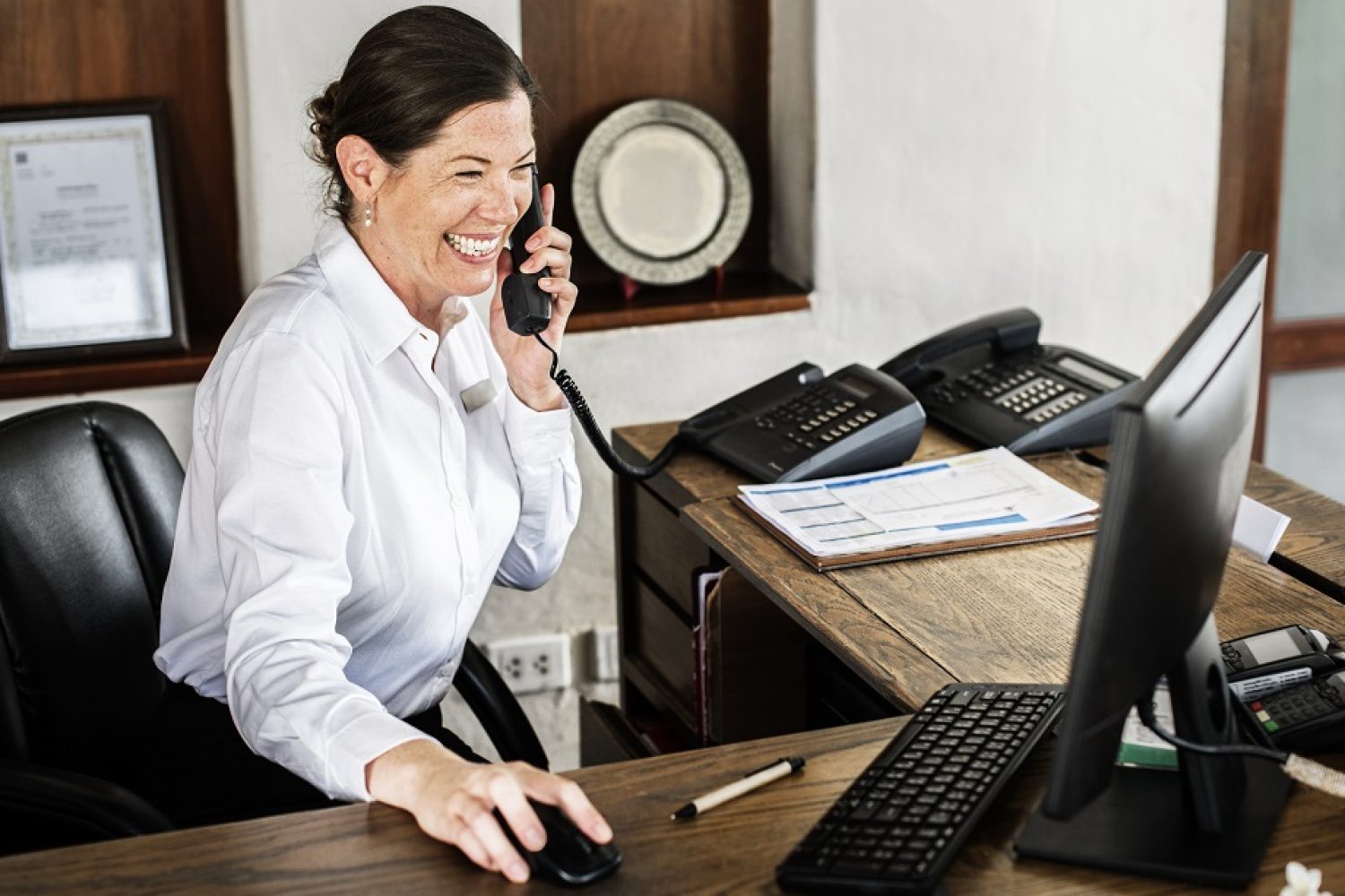 Imagem de uma recepcionista falando ao telefone na recepção de empresa.